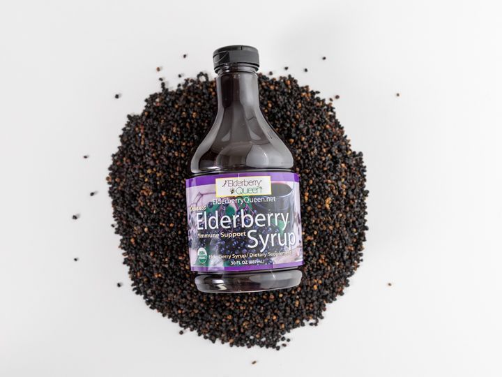 organic elderberry syrup laying on a pile of elderberries
