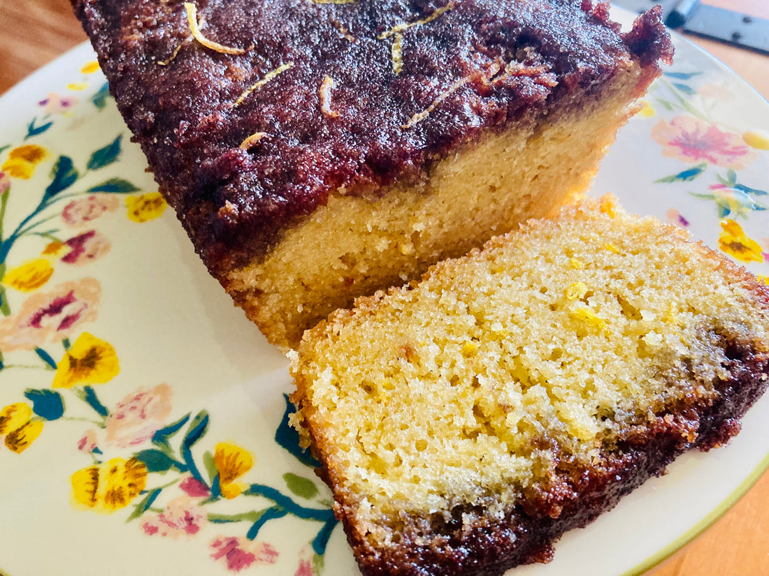 Lemon Elderberry Drizzle cake sliced on a platter
