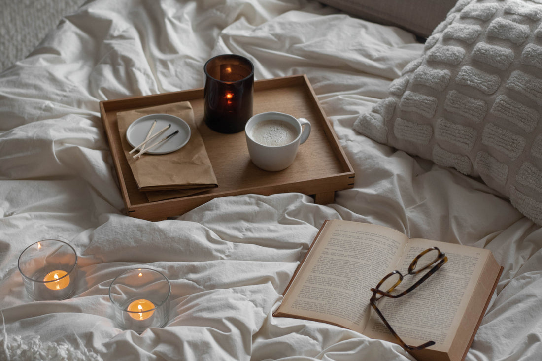 candle, mug, and book on a bed