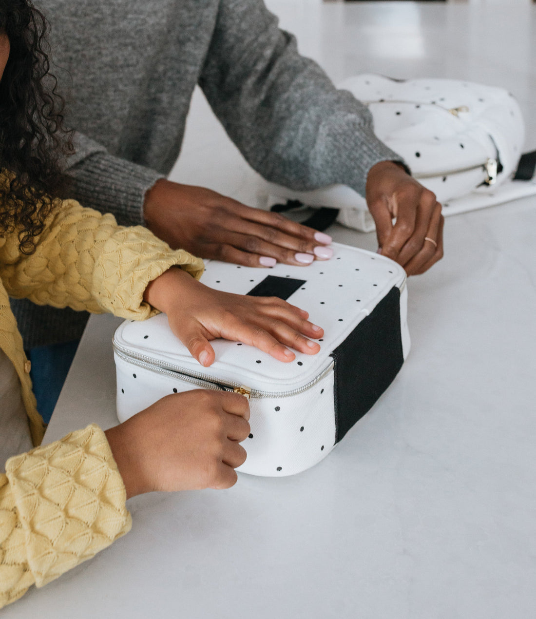 mom zipping up lunch box for daughter
