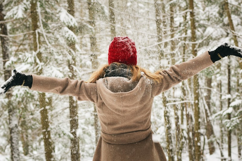 Woman standing in the snow with her arms in the air, free and happy.