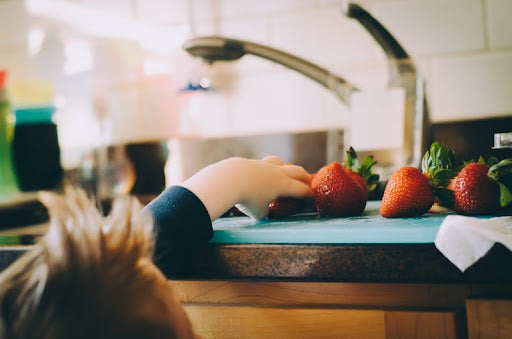 child reaching for strawberries on the counter, nutrition and your child.