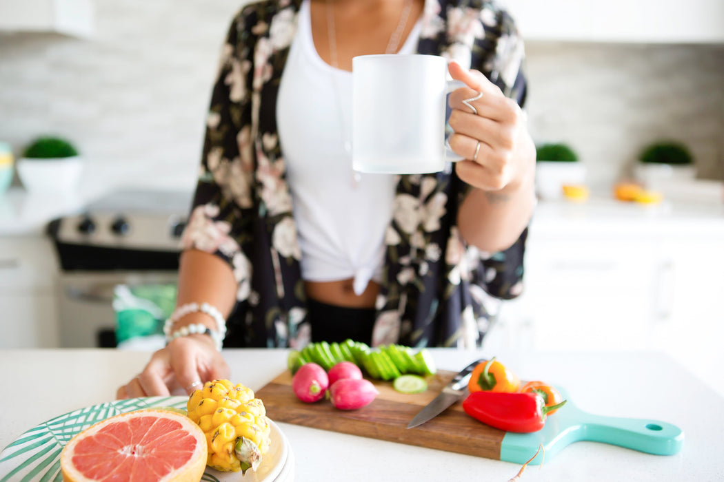 woman with coffee and food around her in the kitchen