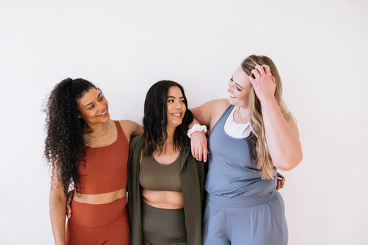three women arms around each other in fitness clothing