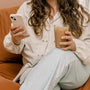 woman lounging with a coffee and scrolling on phone