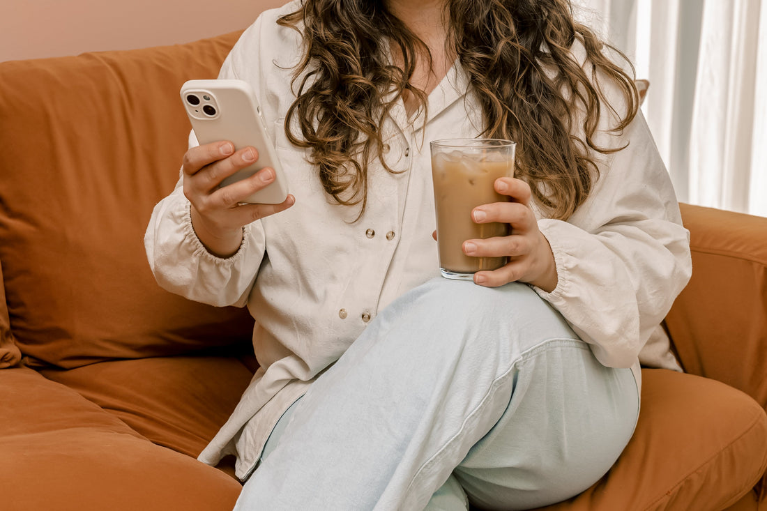 woman lounging with a coffee and scrolling on phone